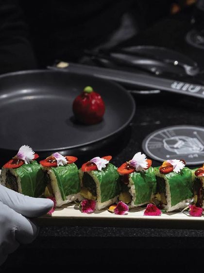 Transport yourself to a world of taste and texture with our delectable sushi. These green-wrapped rolls are garnished with edible flowers for a beautiful presentation.