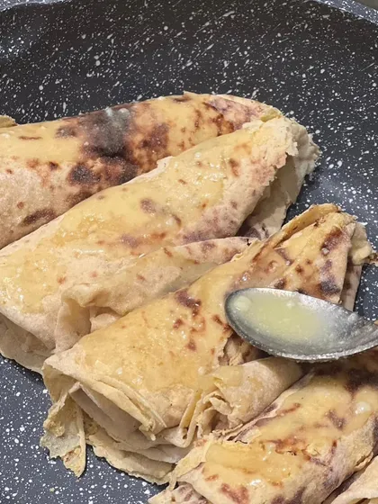Freshly made Puran Poli, a sweet flatbread stuffed with a lentil and jaggery filling, being drizzled with ghee.