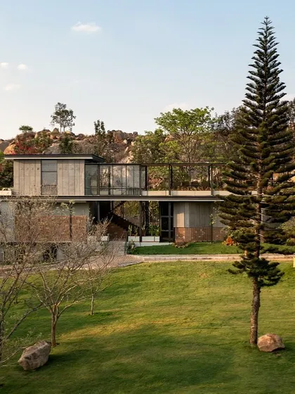 'The Earth' project, viewed from a distance, appears to emerge from the green landscape, with its clean lines and material choices complementing the rocky hills behind it.