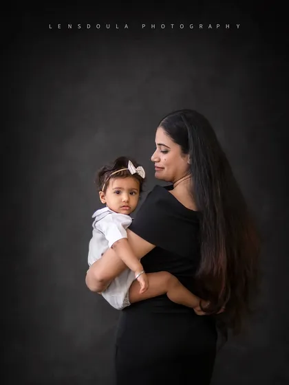 A classic mother-daughter portrait. The way the baby looks directly at the camera while held securely by her mom is simply captivating.