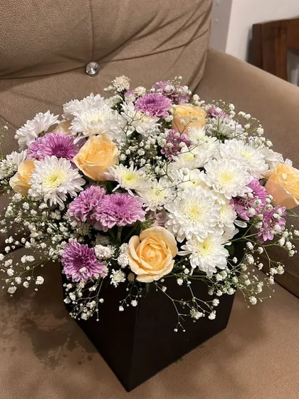 A beautiful flower box arrangement for Mother's Day. We combined peach roses with white and purple chrysanthemums and baby's breath for a soft and elegant look.