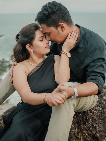An intensely romantic close-up of the couple on a rock overlooking the sea. Their embrace and proximity convey a deep, passionate connection.