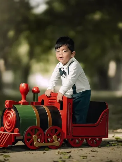 A handsome little conductor on his toy train. The path and trees create a beautiful, natural setting for this classic childhood portrait.