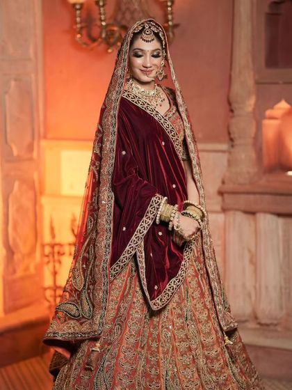 A full-length shot that captures the grandeur of her velvet lehenga and the royal setting. The makeup is designed to complement this majestic look.
