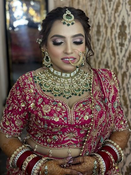 A soft, romantic moment captured. The bride's eyes are closed, showing off the beautiful pink and shimmer eyeshadow work that complements her outfit.