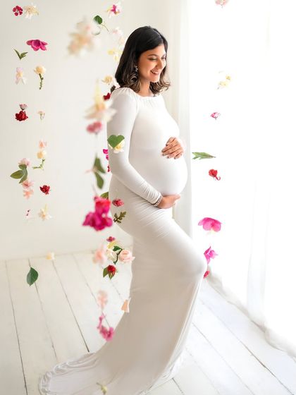 A solo portrait of the mom-to-be surrounded by a cascade of falling petals. Her happy expression perfectly captures the joy of this special time.