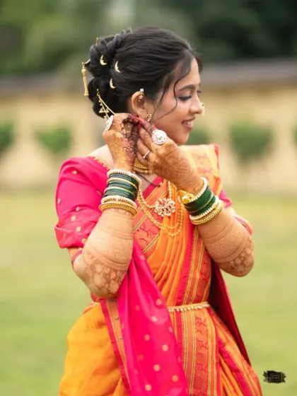 The bride adjusting her earring, a classic shot that showcases her intricate henna and traditional accessories.