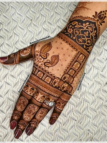 A beautiful back-hand design filled with traditional elements. It includes rows of elephants, pairs of peacocks, and floral patterns on the fingers.