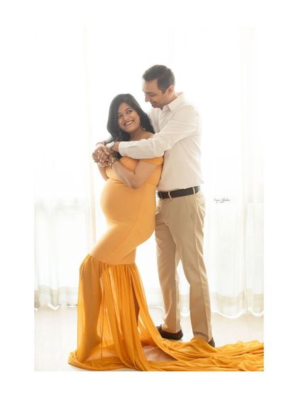 A full-length portrait of an expecting couple, showcasing the beautiful flow of the maternity gown. This pose is elegant and highlights the mother's beautiful silhouette.