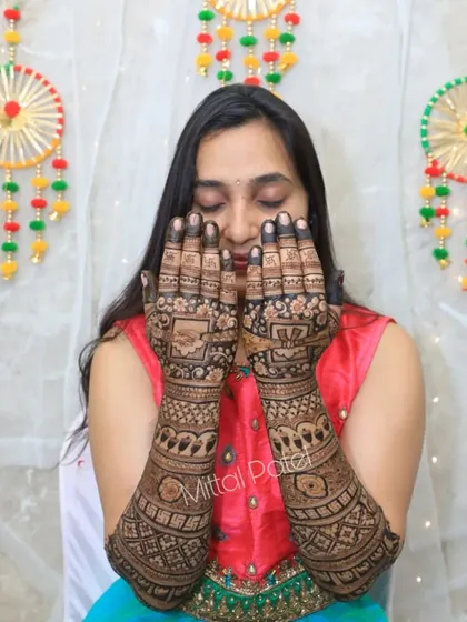 A happy bride showing off her heavy back of hand mehndi. The design is dense and intricate, covering her hands and arms in beautiful traditional patterns.