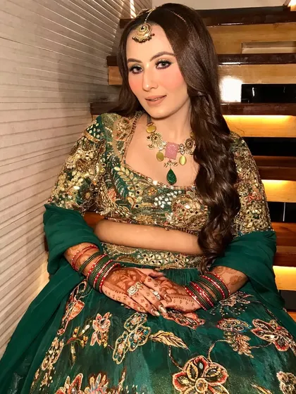 A full-length shot of the Mehendi bride, her colorful necklace and maang tikka perfectly complementing her green outfit.