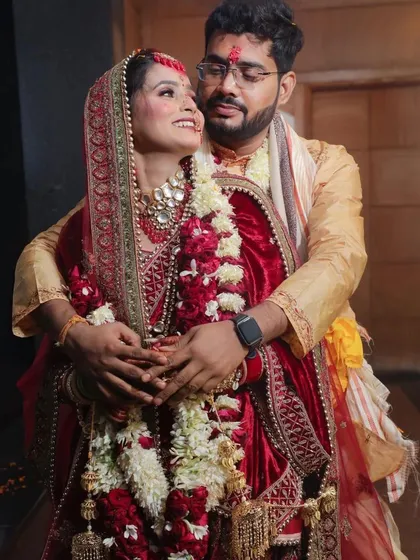 This photo captures the happy and relaxed connection between the newlyweds. The groom embraces the bride from behind as she looks up at him with a radiant smile. It’s a warm, candid moment that showcases their joy right after the ceremony.