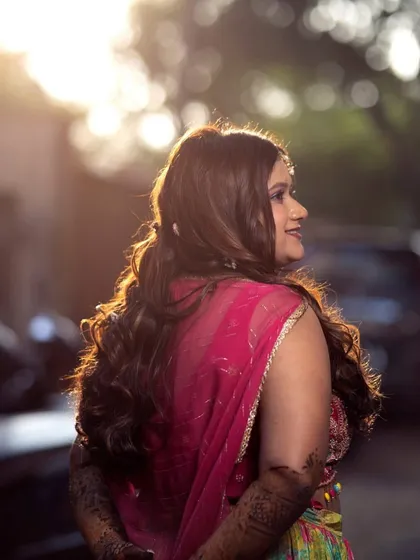 A beautiful backlit shot of the Mehendi bride. The soft waves in her hair and her glowing profile are captured perfectly in the golden hour light.