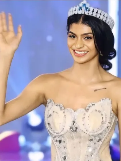 A happy, winning wave to the audience. This close-up shows the bright, engaging smile and the eye makeup designed to connect with the judges and the crowd.