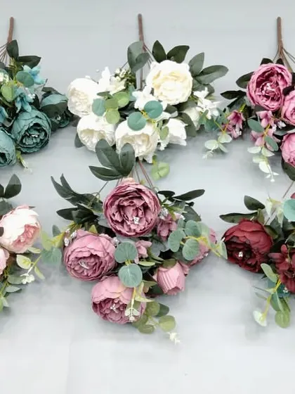 Artificial peony bunches in muted and deep tones like teal, mauve, and burgundy, mixed with eucalyptus leaves.