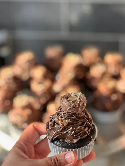 Holding up one of our Ferrero Nutella cupcakes to show off all the delicious details, from the creamy piping to the crunchy hazelnut topping.
