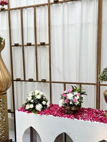 Another view of the traditional welcome table, with a bed of rose petals and elegant floral arrangements in golden vases.