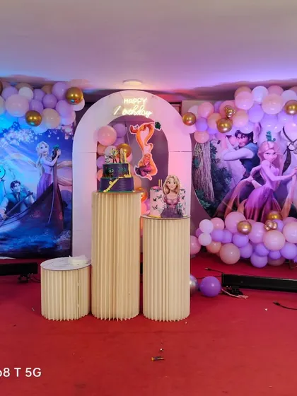 A closer look at the Tangled birthday stage, highlighting the balloon arrangements, arched backdrop, and detailed character posters.