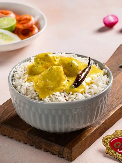 A comforting bowl of Kadhi Chawal, with a vibrant yellow curry and perfectly cooked rice for Gulab Sweets.