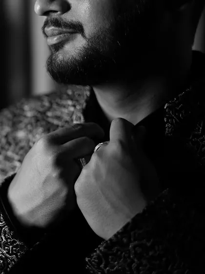A dramatic black and white close up of the groom getting ready, highlighting the details of his outfit and the anticipation of the moment.