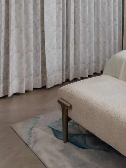 A close-up on the textures in the daughter's room. The plush bouclé fabric of the bench, the abstract pattern of the rug, and the gently patterned curtains all contribute to a layered and cozy feel.