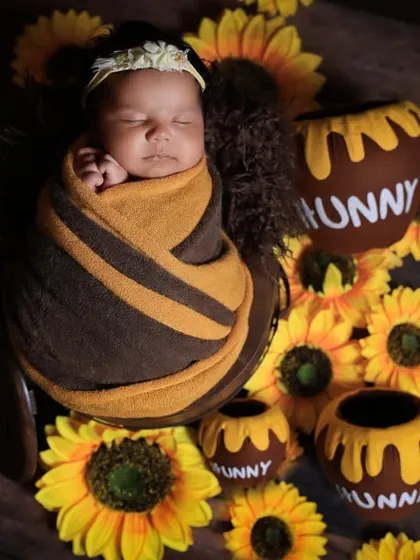 A slightly different take on our 'hunny' pot theme, this image shows the baby swaddled in bee-like stripes, creating a cohesive and adorable Winnie the Pooh inspired newborn portrait.
