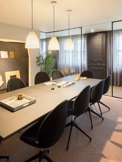 A sophisticated conference room with dark, moody tones and soft lighting. The design creates a focused and intimate setting for important meetings and presentations.