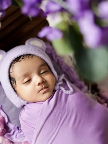 A close-up of a newborn wearing an adorable bear bonnet. We focus on capturing their delicate features, from their soft cheeks to their tiny nose.