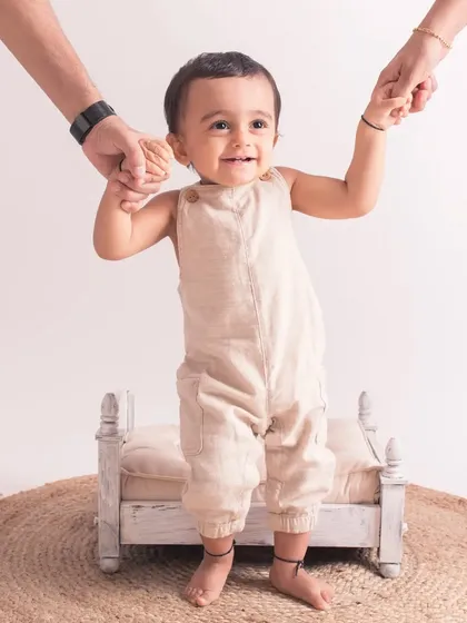 Taking his first steps with a little help from mom and dad. A beautiful moment captured during his first birthday session.