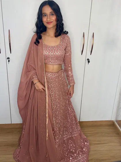 The full outfit shot shows how the simple makeup and hair balance the detailed embroidery of her lehenga.