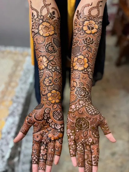 A still shot of the full floral engagement mehendi. The pattern is continuous and flowing, with flowers of different sizes creating a garden on the arms.