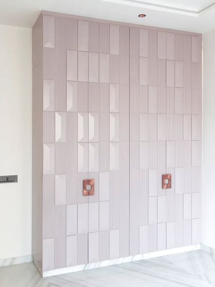 This wardrobe showcases a unique geometric 3D pattern on its shutters, finished in a soft, light color. It serves as both a storage unit and a piece of art.