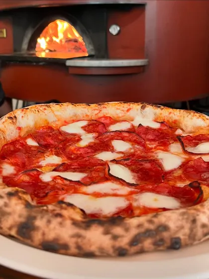 A classic pepperoni pizza getting that wood-fire kiss. The heat from the oven brings out all the spicy notes of the salami.