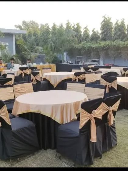 A simple yet functional outdoor seating arrangement with round tables covered in black and gold linen.