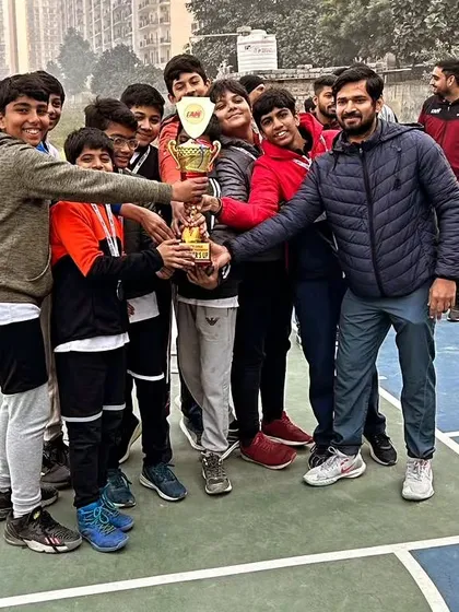 A coach and his team celebrating with the trophy after a big win. The bond between our coaches and players is our biggest strength.