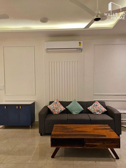 This living room showcases a minimalist aesthetic with a focus on clean lines. I used wall mouldings and fluted panels to add texture to the walls, paired with a simple dark sofa and a blue cabinet for a pop of color.