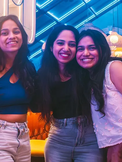 Three friends posing under the blue neon lights.