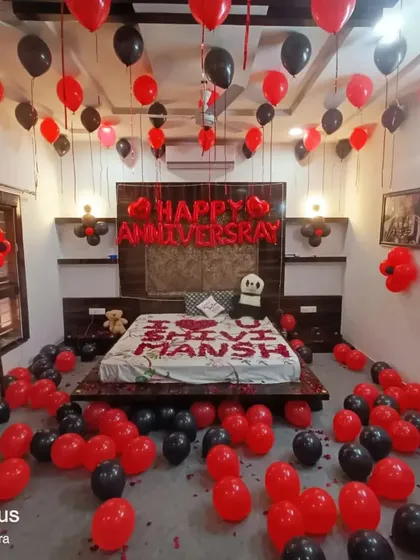 A personalized anniversary room setup in red and black. I used rose petals to write the couple's names on the bed and filled the room with balloons for a dramatic and personal touch.