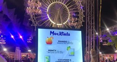 A digital 'Mocktails' menu displayed at an event with a Ferris wheel in the background, showing our services for non-alcoholic options.