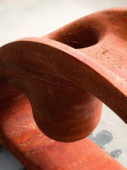 A detail shot of the Samaveta Console, showcasing the beautiful, raw texture and rich color variations of the red travertine. The curves are hand-finished to create a smooth, tactile experience.