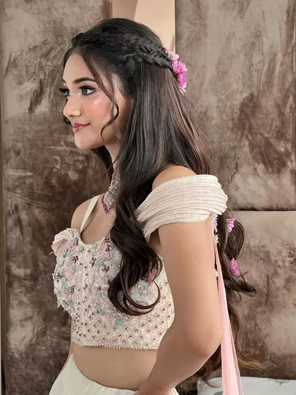 A side view of the floral braid half-updo, perfect for a Haldi or Mehendi. The flowers add a fresh and festive touch.