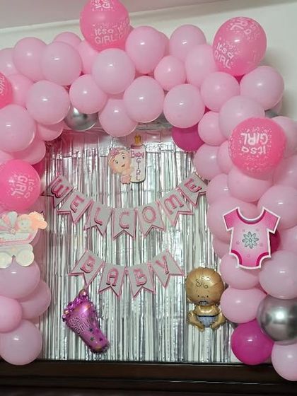 A 'Welcome Baby' balloon arch and shimmer curtain setup over a headboard, creating a perfect photo spot at home.