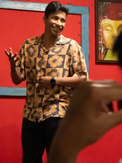 A comedian engaging with the audience during our interactive and fluid comedy night, set against our signature red wall.