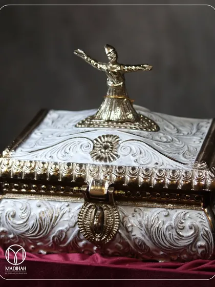 A detailed look at the Sufi-inspired Rajwada Chest, featuring a sculpted whirling dervish in a gold finish atop an intricately carved white and gold box. This piece was custom-made to honor the client's rich cultural and artistic heritage.