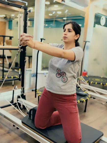 Kneeling exercises on the reformer challenge your balance and core. Here, a client focuses on controlled arm movements, strengthening her shoulders and upper back.