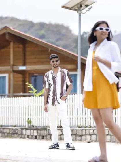 A fun, quirky pose in front of wooden cabins. This shows the couple's playful side and adds variety to the pre-wedding album.