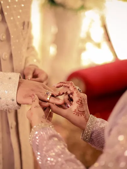 A macro shot capturing the intimate moment of the ring being placed on the finger during an engagement ceremony.