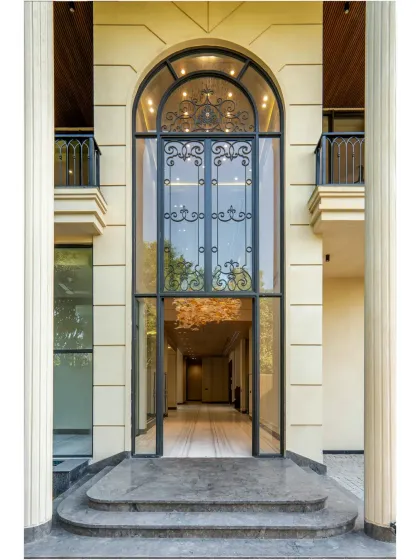 The grand arched entrance of the Sultanpur farmhouse, featuring intricate wrought iron detailing. This entrance is designed to create a lasting impression, blending classic elegance with modern aesthetics and flooding the interior with light.