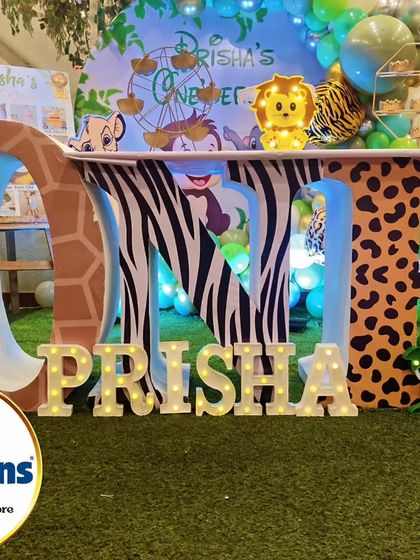 A close-up of the custom 'ONE' table, with each letter decorated in a different animal print like giraffe, zebra, and leopard.