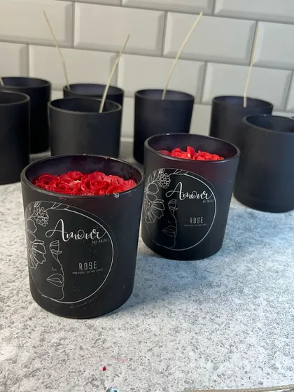 Our rose-scented candle in a sleek, black frosted jar. The candle is topped with red wax rose petals, combining a modern look with a classic floral touch.